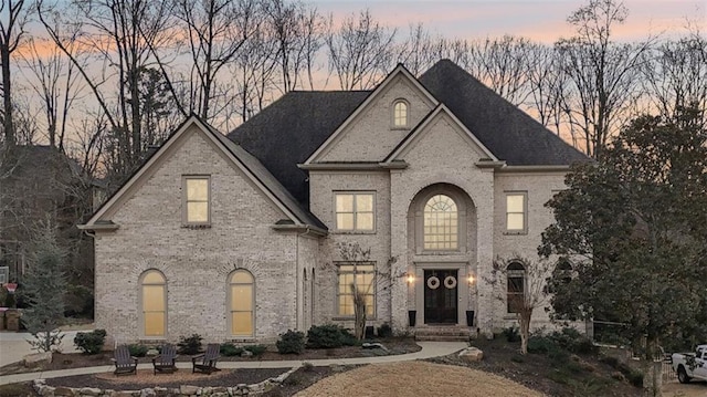 french provincial home featuring brick siding and an outdoor fire pit