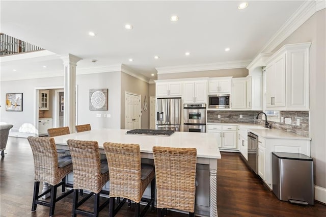 kitchen featuring stainless steel appliances, light countertops, white cabinets, backsplash, and a center island