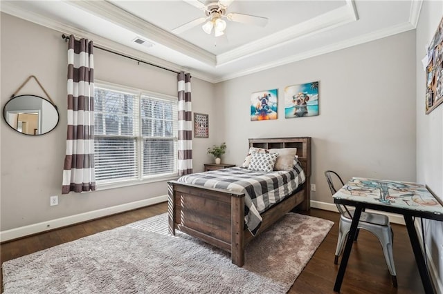 bedroom with visible vents, crown molding, a raised ceiling, and wood finished floors