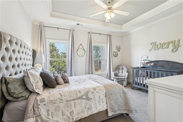 bedroom with a tray ceiling, carpet, visible vents, and ornamental molding