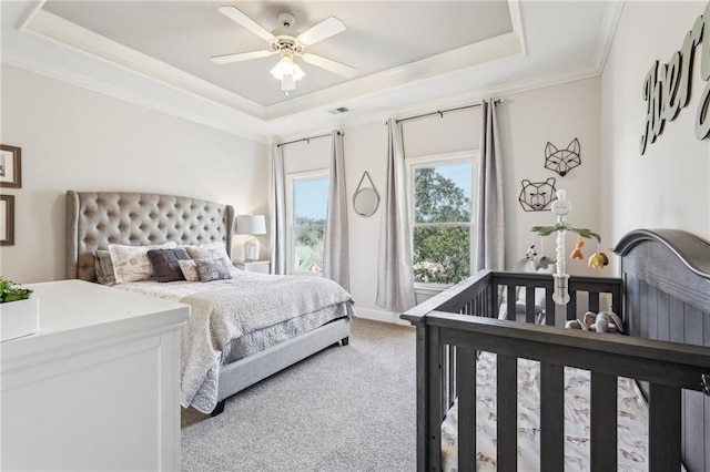 bedroom with visible vents, crown molding, light colored carpet, a raised ceiling, and a ceiling fan