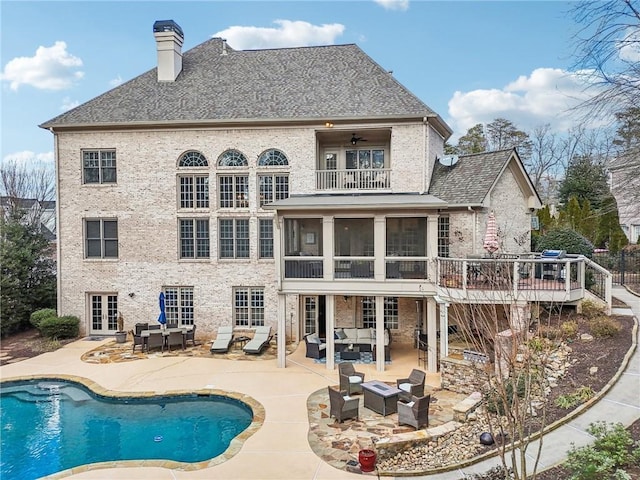 back of property with a patio, a balcony, a chimney, french doors, and an outdoor hangout area