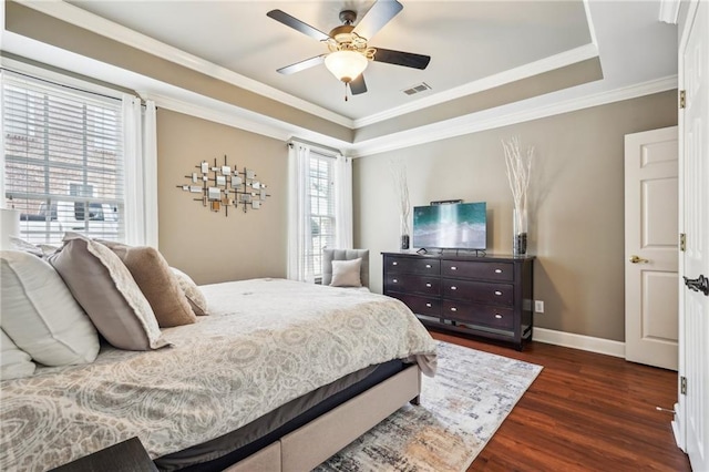 bedroom featuring a tray ceiling, dark wood-style floors, visible vents, and ornamental molding