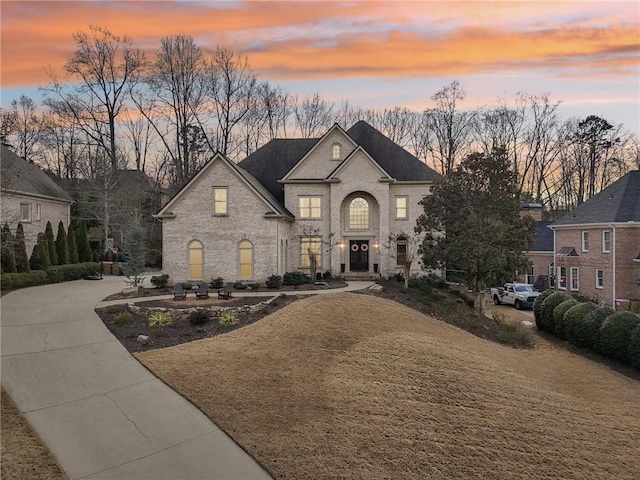 french provincial home featuring brick siding and driveway