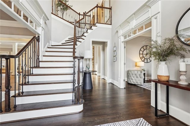 stairs featuring wood finished floors, baseboards, and a towering ceiling