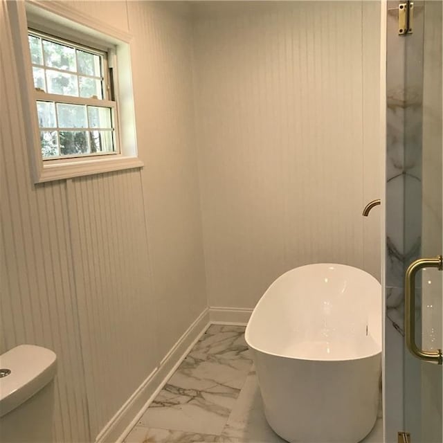 full bath featuring marble finish floor, a soaking tub, a shower with shower door, and baseboards