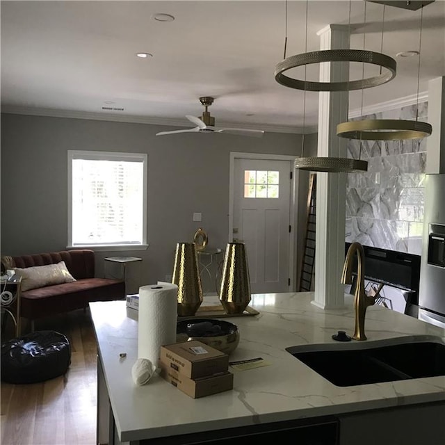 kitchen featuring a wealth of natural light, crown molding, decorative backsplash, and a sink