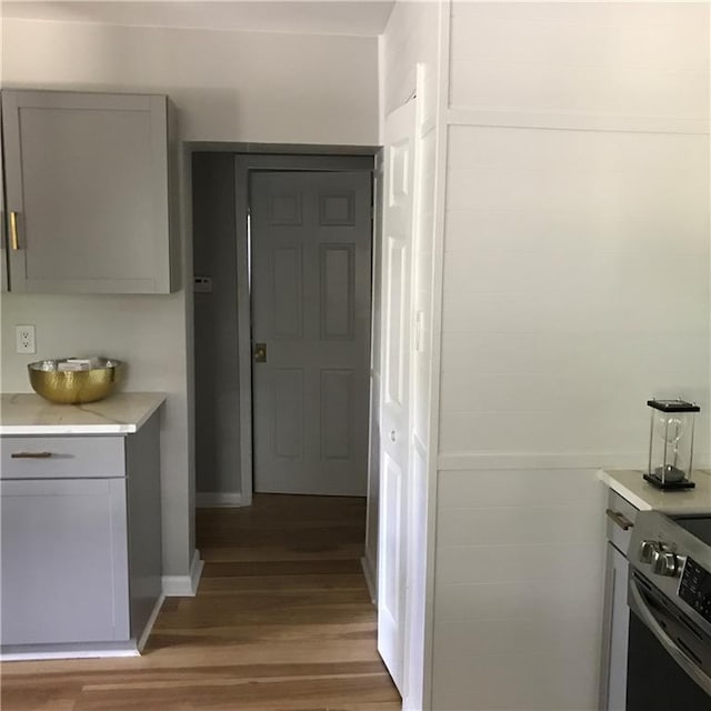 kitchen with baseboards, light wood-style floors, gray cabinets, light countertops, and stainless steel range with electric stovetop