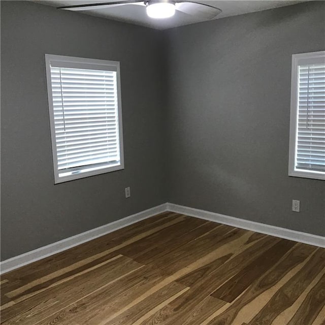 unfurnished room featuring dark wood-type flooring, a ceiling fan, and baseboards