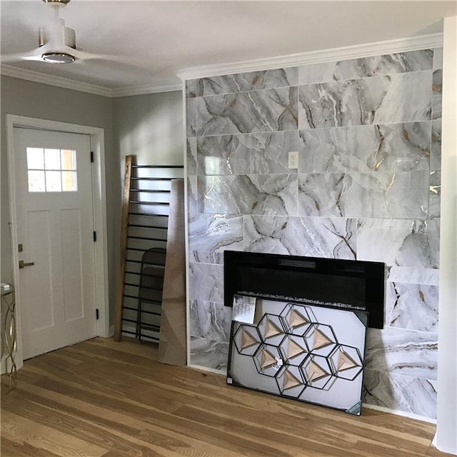 foyer entrance with a premium fireplace, wood finished floors, and crown molding