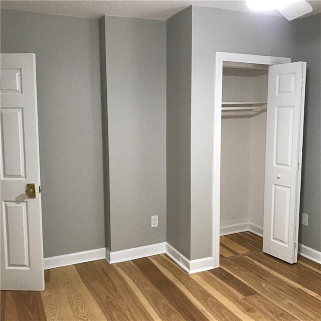 unfurnished bedroom featuring a closet, baseboards, and wood finished floors