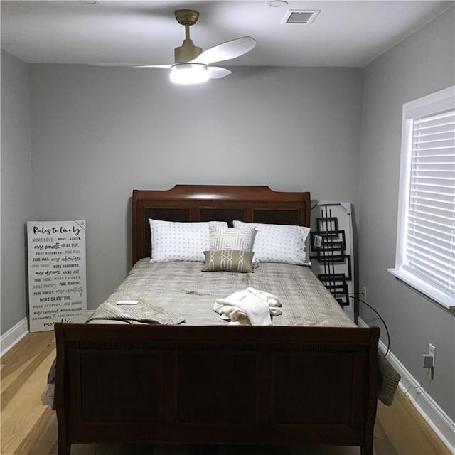 bedroom featuring a ceiling fan, light wood-type flooring, visible vents, and baseboards