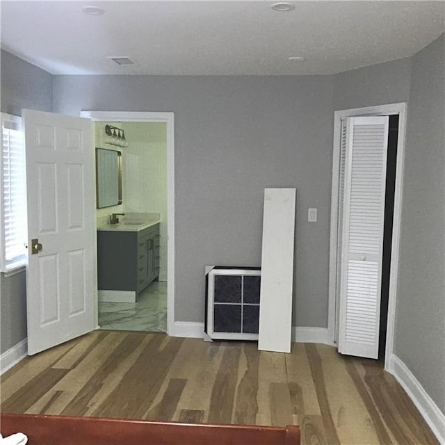 unfurnished bedroom featuring a sink, baseboards, and wood finished floors