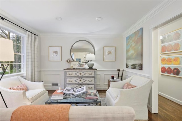 living area featuring a wainscoted wall, wood finished floors, visible vents, and ornamental molding