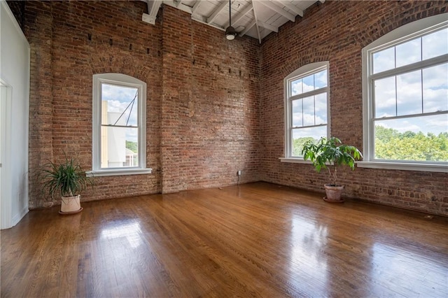 1596 Cleveland Ave Unit 301, East Point, GA 30344 - spare room with healthy amount of natural light, brick wall, a towering ceiling, wood finished floors, and beamed ceiling