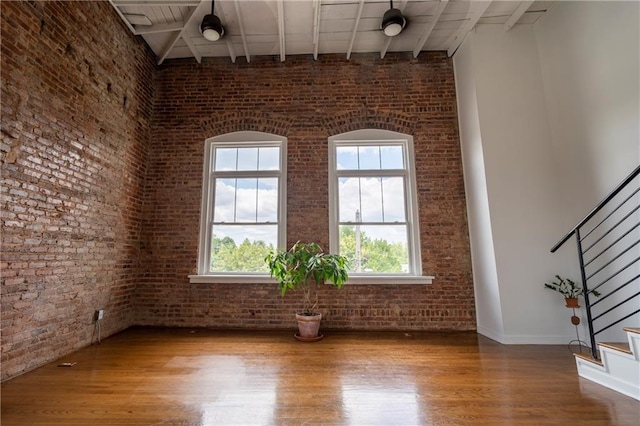1596 Cleveland Ave Unit 301, East Point, GA 30344 - spare room with brick wall, wood finished floors, stairway, beamed ceiling, and a towering ceiling