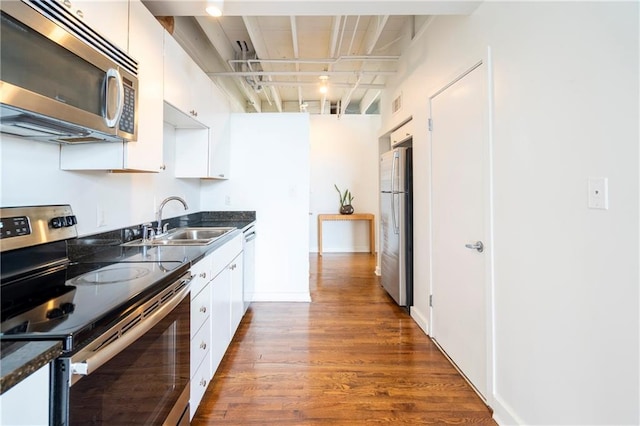 1596 Cleveland Ave Unit 301, East Point, GA 30344 - kitchen featuring appliances with stainless steel finishes, dark countertops, dark wood-style flooring, and white cabinetry