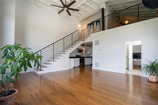 1596 Cleveland Ave Unit 301, East Point, GA 30344 - unfurnished living room with a towering ceiling, ceiling fan, stairway, wood finished floors, and beam ceiling