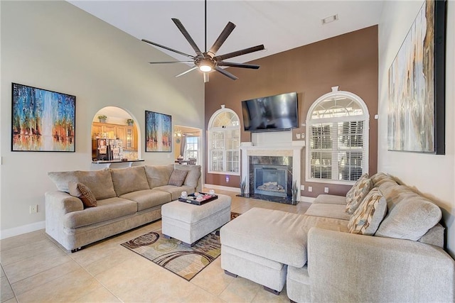 living area featuring light tile patterned floors, a high ceiling, a premium fireplace, visible vents, and baseboards