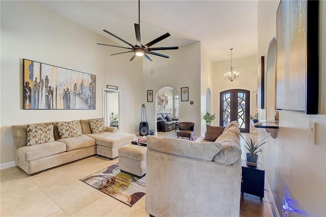 living area featuring arched walkways, light tile patterned floors, visible vents, a high ceiling, and ceiling fan with notable chandelier