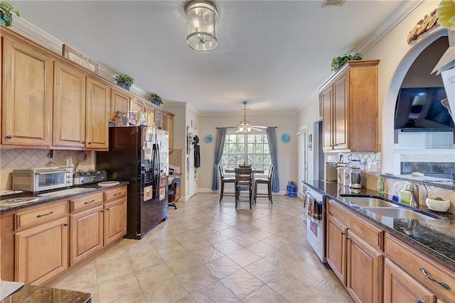 kitchen with dark stone counters, black refrigerator with ice dispenser, a sink, and ornamental molding