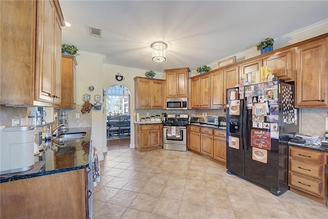 kitchen featuring visible vents, appliances with stainless steel finishes, brown cabinetry, ornamental molding, and a sink