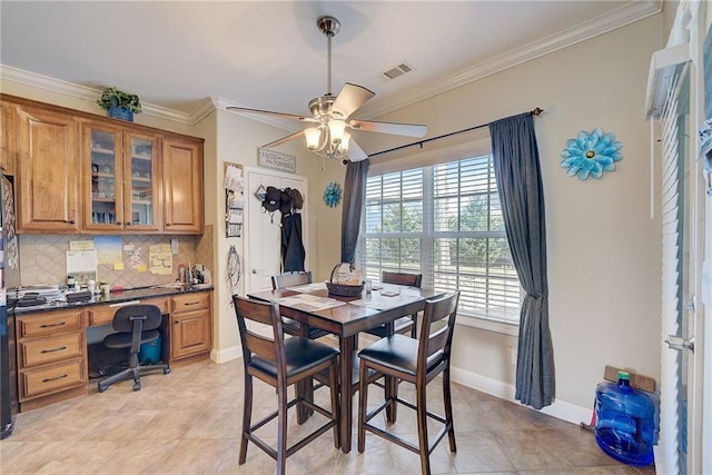 dining room featuring light tile patterned floors, a ceiling fan, baseboards, visible vents, and crown molding