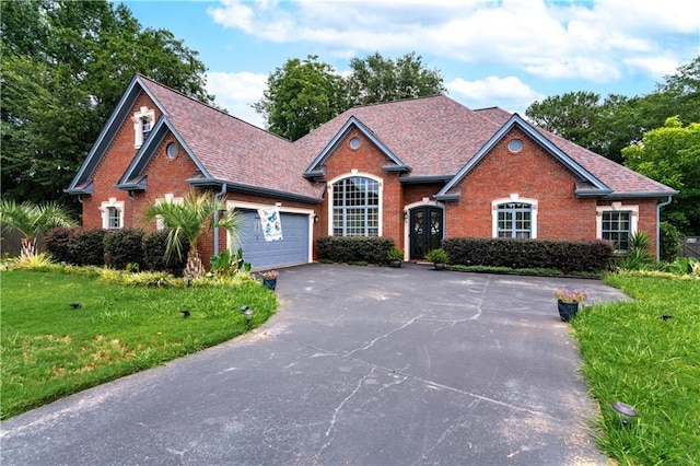 traditional-style home with driveway, an attached garage, a front yard, and brick siding