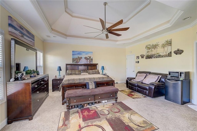 bedroom with ornamental molding, a tray ceiling, and light colored carpet