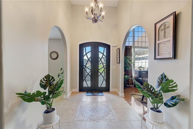 entryway with an inviting chandelier, baseboards, arched walkways, and french doors