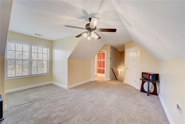 additional living space with baseboards, visible vents, vaulted ceiling, and carpet flooring