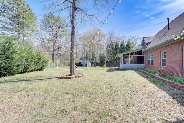 view of yard featuring a shed, an outdoor structure, fence, and a sunroom