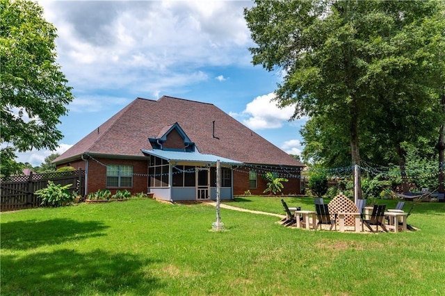 back of house with a sunroom, a fire pit, a lawn, and brick siding