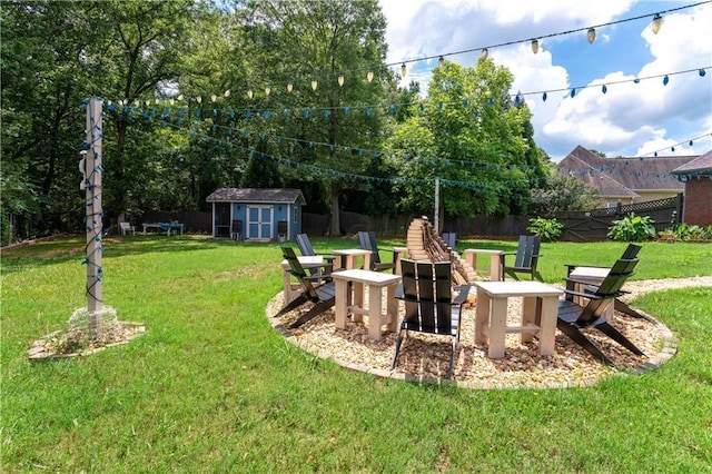 view of yard featuring a storage shed, a fenced backyard, a fire pit, and an outbuilding