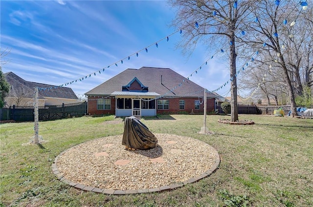 back of property with a sunroom, a fenced backyard, a yard, and brick siding