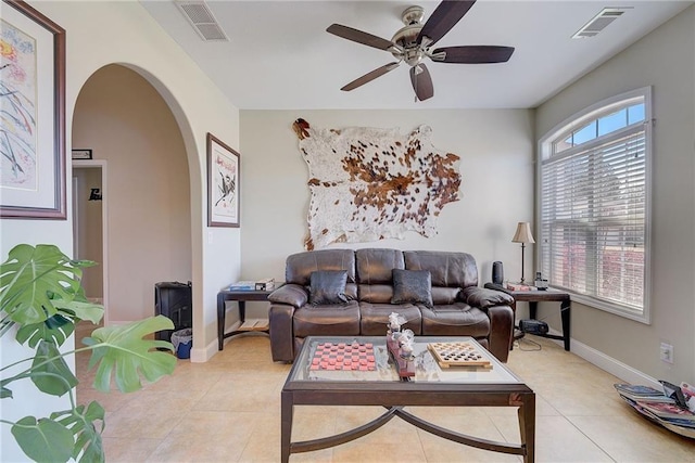 living room featuring arched walkways, visible vents, ceiling fan, and light tile patterned floors