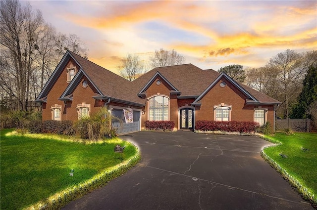 view of front of property with driveway, a garage, fence, a yard, and brick siding