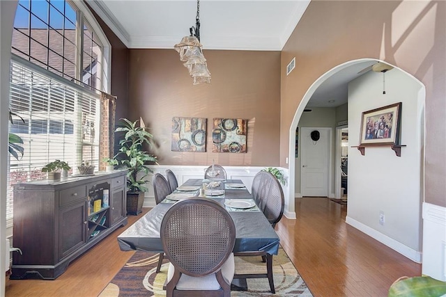 dining space with baseboards, visible vents, arched walkways, and wood finished floors