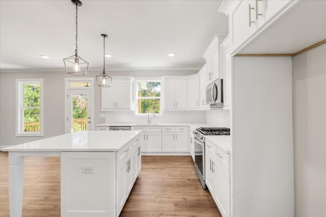 kitchen with a kitchen island, decorative light fixtures, white cabinetry, stainless steel appliances, and sink