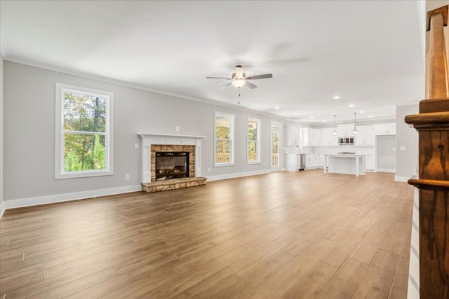 unfurnished living room featuring ceiling fan, a healthy amount of sunlight, and ornamental molding