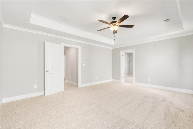 carpeted spare room featuring a raised ceiling, ceiling fan, and crown molding