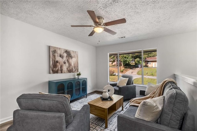 living room with a textured ceiling, ceiling fan, and light hardwood / wood-style floors