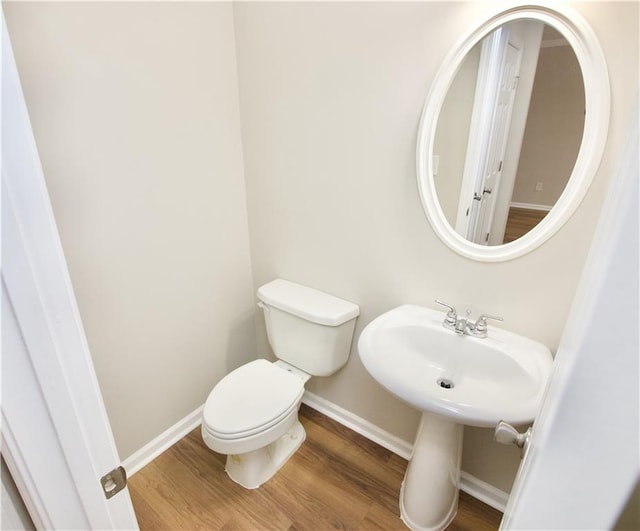 bathroom with baseboards, toilet, and wood finished floors