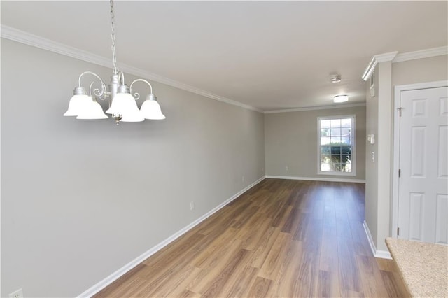 interior space with a notable chandelier, crown molding, baseboards, and wood finished floors