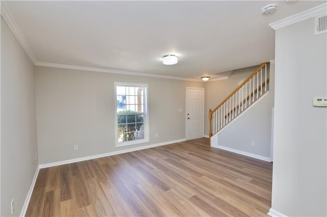 unfurnished room featuring ornamental molding, stairway, wood finished floors, and baseboards