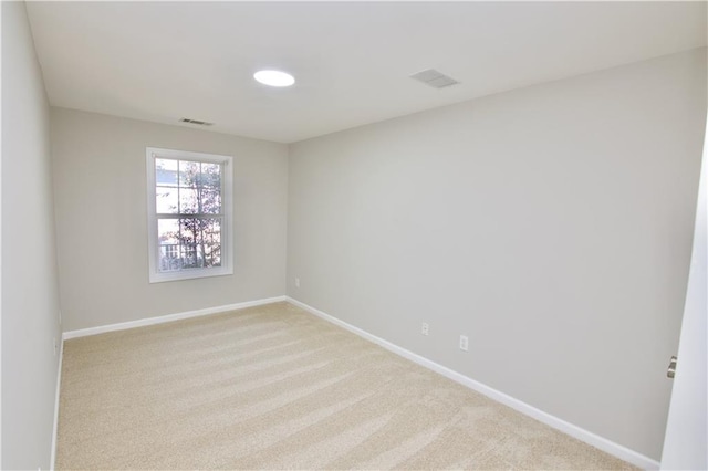 empty room with light colored carpet, visible vents, and baseboards