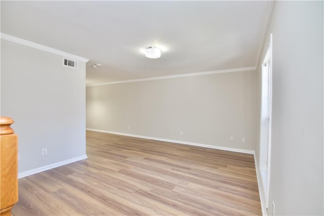 spare room featuring light wood-type flooring, visible vents, crown molding, and baseboards