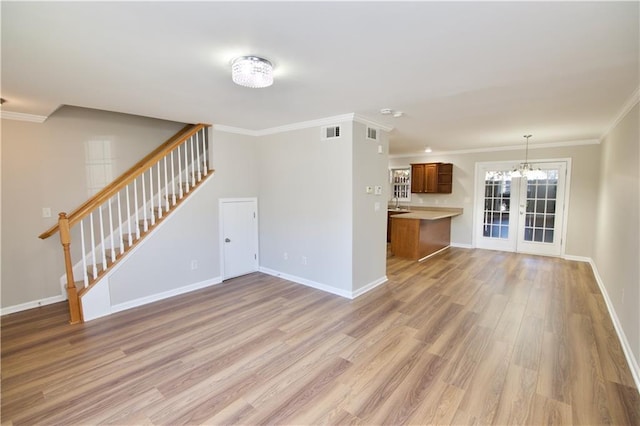 unfurnished living room with light wood-style floors, visible vents, stairway, and baseboards