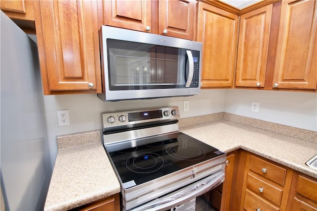 kitchen featuring brown cabinetry, stainless steel appliances, and light countertops