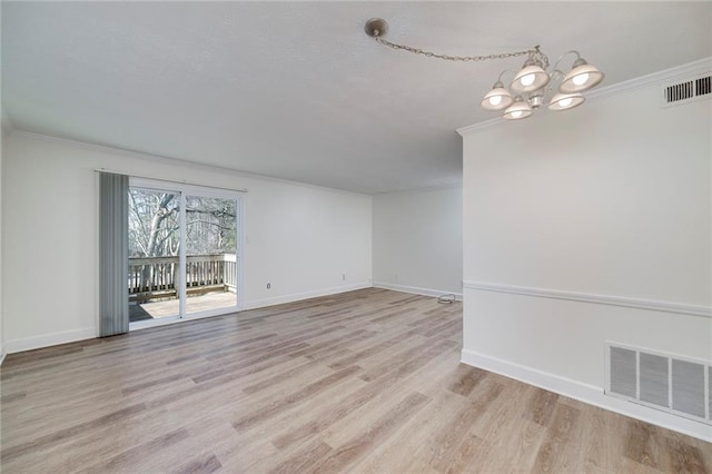 empty room featuring ornamental molding, light wood-type flooring, and a notable chandelier